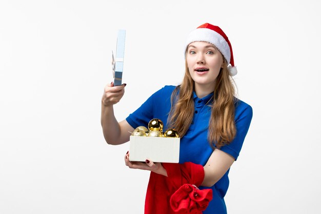 Front view of female courier with holiday toys on a white wall