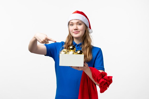 Front view of female courier with holiday toys on white wall