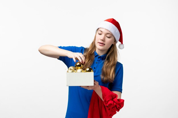 Front view of female courier with holiday toys on white wall