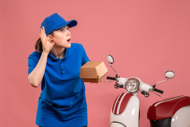 ピンクの仕事の配達の均一なサービスの仕事の自転車の労働者のピザの女性を聞いている小さな食品パッケージの正面図の女性の宅配便