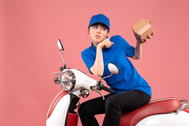 Front view female courier with little food package on pink job color uniform worker food delivery