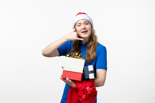 Front view of female courier with presents and toys on the white wall