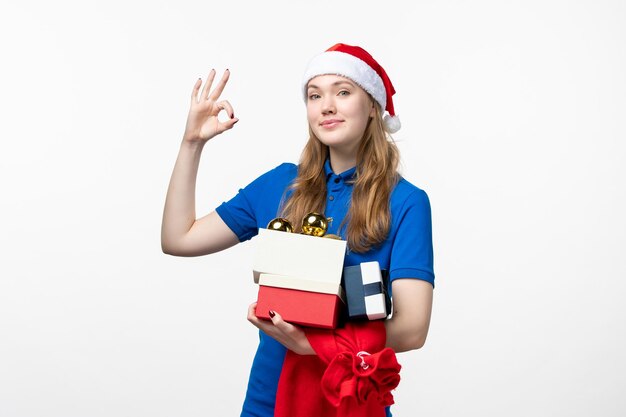 Front view of female courier with presents and toys on white wall