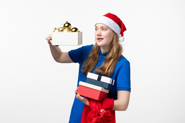 Front view of female courier with toys and presents on a white wall