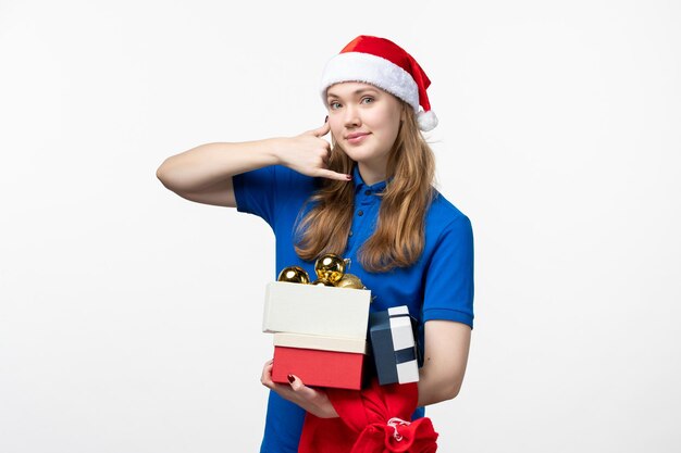 Front view of female courier with toys and presents on white wall