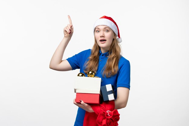 Front view of female courier with toys and presents on white wall