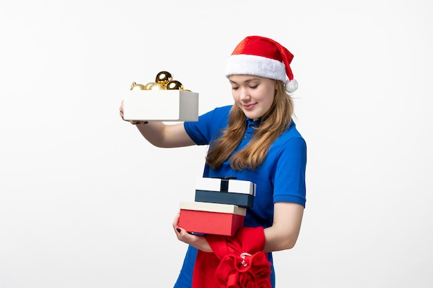 Front view of female courier with toys and presents on white wall