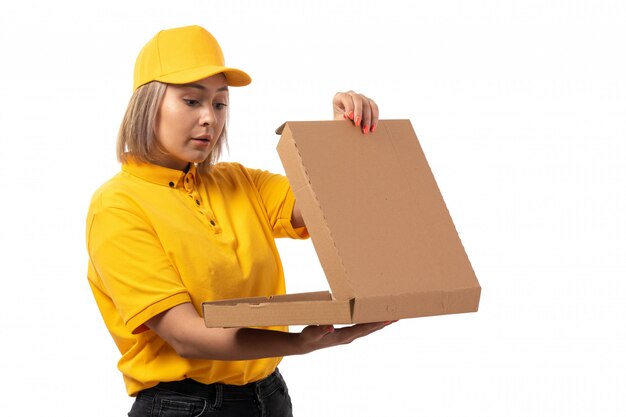 A front view female courier in yellow cap yellow shirt holding pizza box surprissed on white