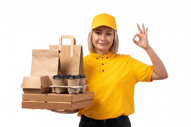 노란색 셔츠 노란색 모자와 피자 상자 커피 컵을 들고 검은 청바지에 전면보기 여성 택배 미소 표시 괜찮아 기호 화이트