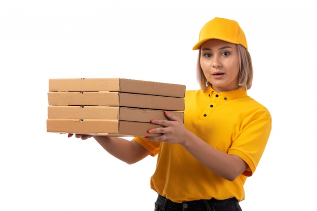 黄色のシャツの黄色のキャップと白のピザの箱を保持している黒のジーンズで正面の女性宅配便