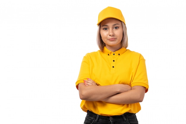 A front view female courier in yellow shirt yellow cap and black jeans posing on white