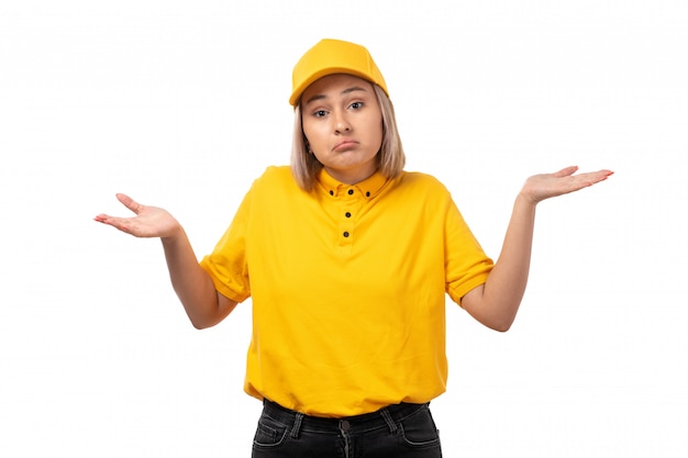 A front view female courier in yellow shirt yellow cap and black jeans posing with do not know expression on white