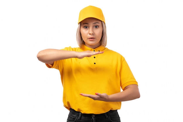 黄色のシャツイエローキャップと白の彼女の手でサイズを示す黒のジーンズで正面女性宅配便