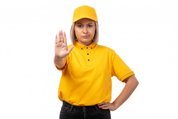 A front view female courier in yellow shirt yellow cap and black jeans showing stop sign on white