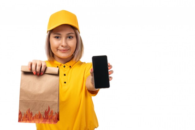 노란색 셔츠 노란색 모자 전면보기 여성 택배는 흰색에 음식 미소 스마트 폰 및 패키지를 들고