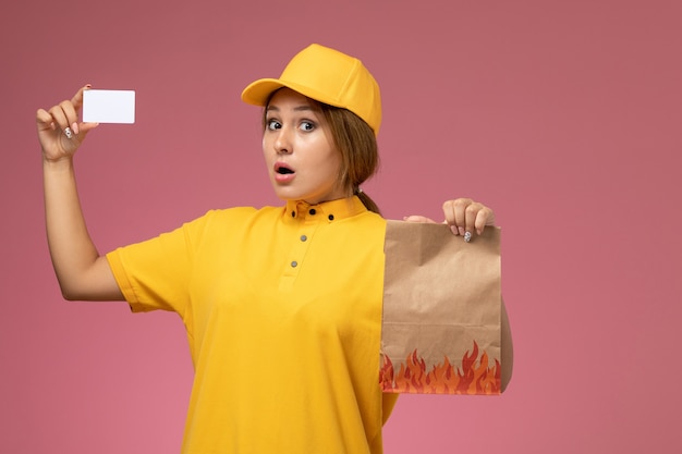 분홍색 배경에 흰색 카드와 음식 패키지를 들고 노란색 유니폼 노란색 케이프 전면보기 여성 택배 유니폼 배달 작업 컬러 사진 여성