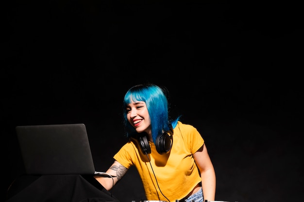 Front view female dj checking settings on laptop