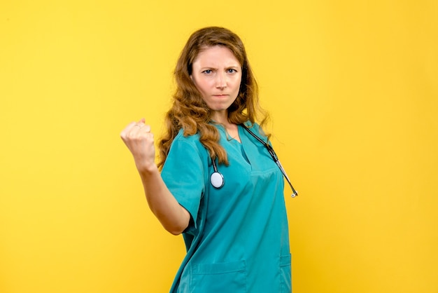 Вид спереди женщина-врач сердится на желтом пространстве