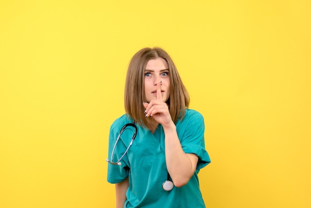 노란색 공간에 조용히 요구하는 전면보기 여성 의사