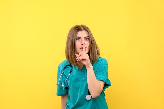 Вид спереди женщина-врач просит молчать на желтом пространстве