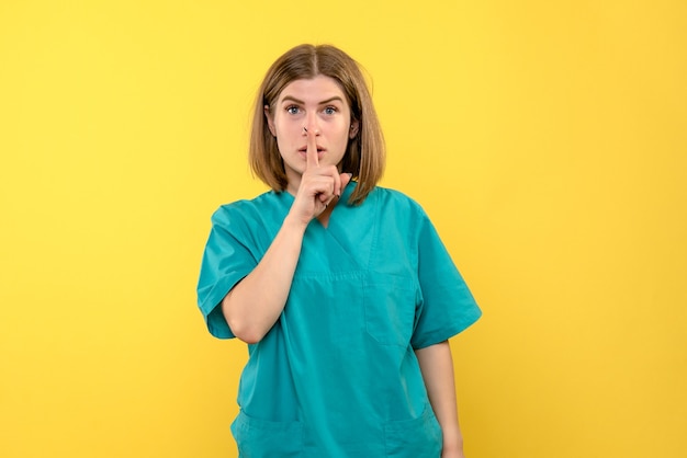 Front view female doctor asking to be quiet on yellow space