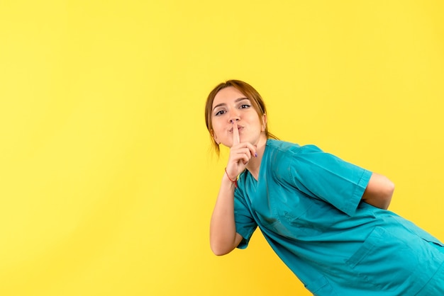 Front view female doctor asking to be quiet on yellow space