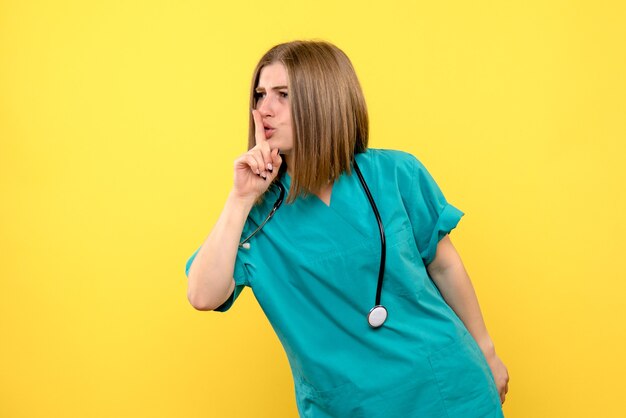 Front view female doctor asking to be silent on yellow space