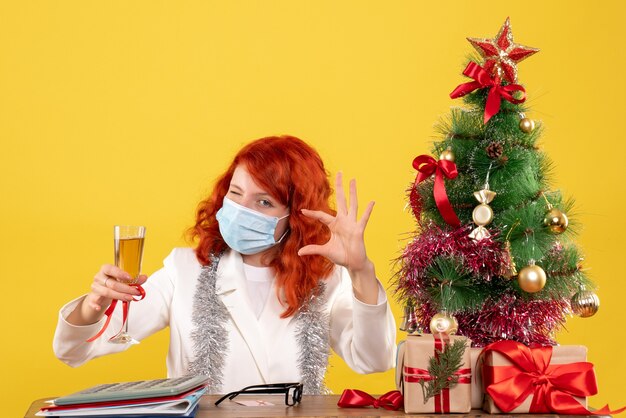 Вид спереди женщина-врач празднует рождество с бокалом шампанского