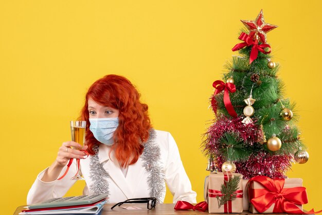 Front view female doctor celebrating xmas with glass of champagne