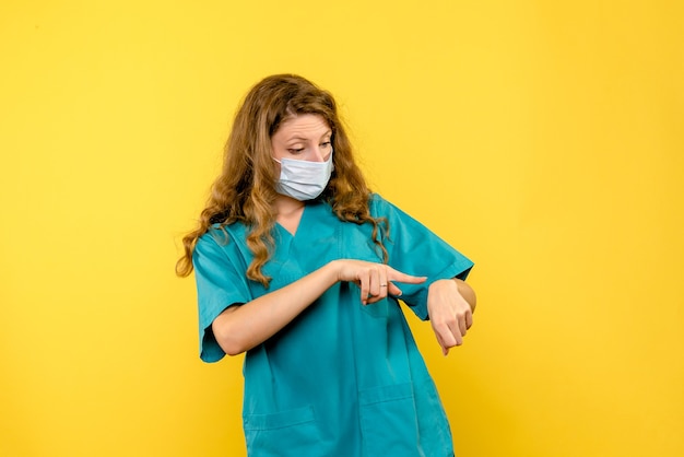 Front view female doctor checking time on yellow space