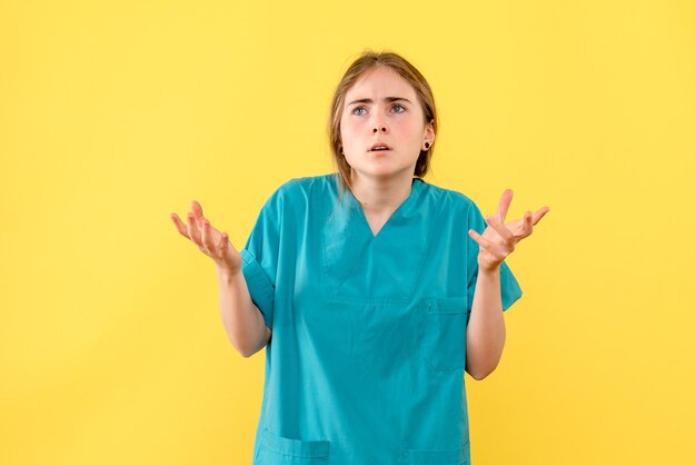 Вид спереди женщина-врач смущена на желтом фоне, медик, эмоция, больница, вирус здоровья