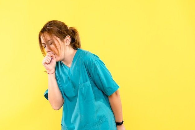 黄色い空間で咳をする正面図の女性医師