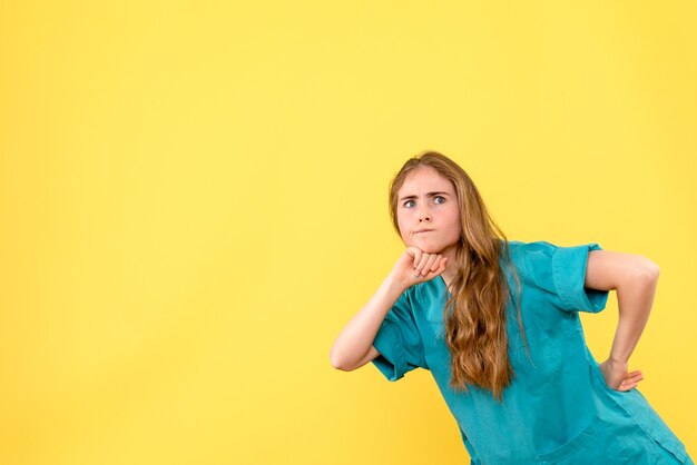 Front view female doctor curiously looking on yellow background health medic emotion virus