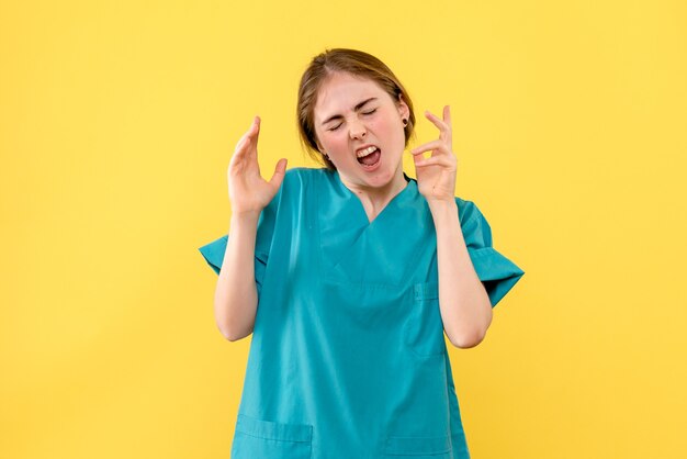 Medico femminile di vista frontale scontento sul medico dell'ospedale di emozione di salute del fondo giallo