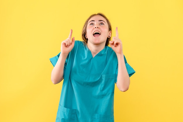 Medico femminile di vista frontale eccitato su un medico dell'ospedale di salute di emozione del fondo giallo