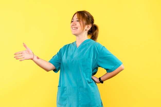 Front view female doctor greeting someone on yellow space
