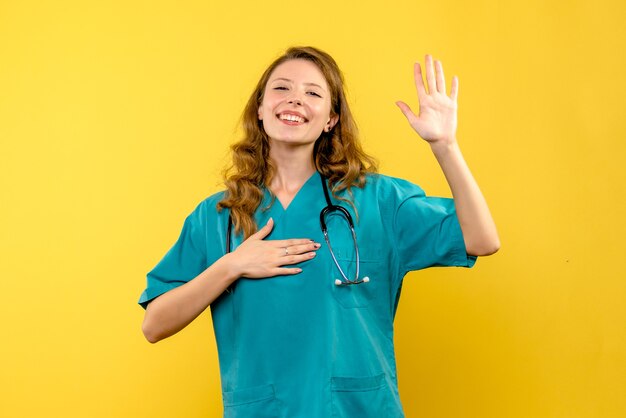 Front view female doctor happily smiling on yellow space