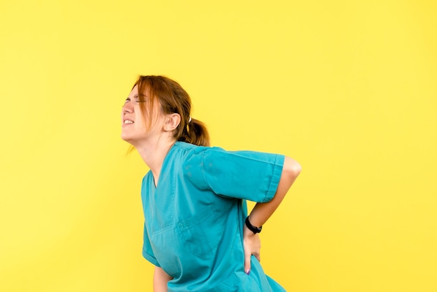 Front view female doctor having backache on yellow space