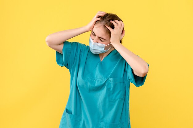 노란색 배경 covid- 병원 건강 유행에 두통을 가진 전면보기 여성 의사