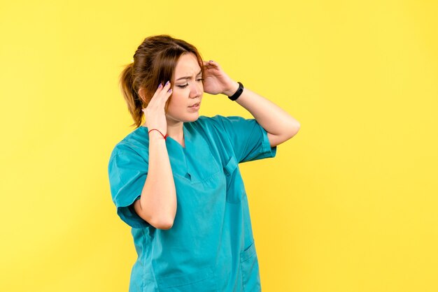 Вид спереди женщина-врач с головной болью на желтом пространстве