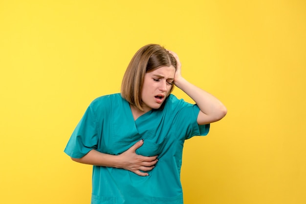 Foto gratuita medico femminile di vista frontale che ha problemi di salute sullo spazio giallo