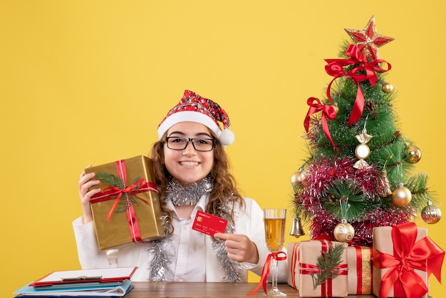 Front view female doctor holding bank card and present