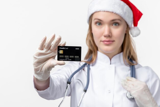 Front view of female doctor holding bank card on the white wall