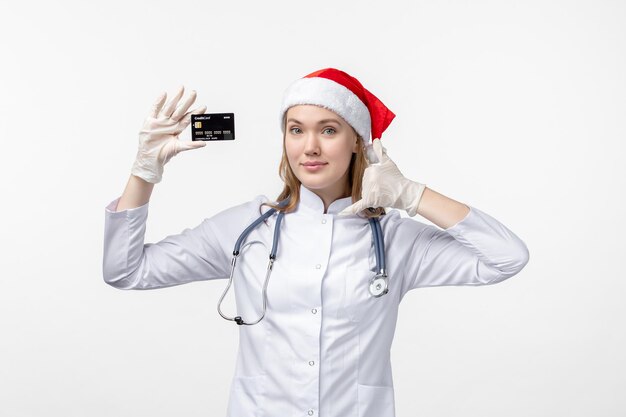 Front view of female doctor holding bank card on the white wall