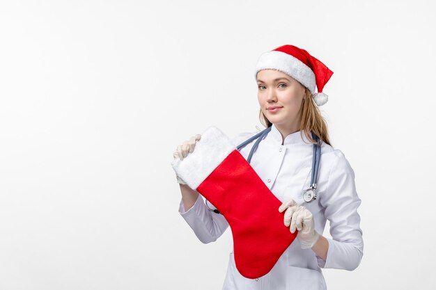 Front view of female doctor holding big holiday sock on white wall