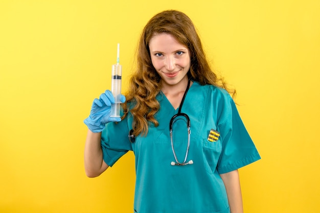 Front view female doctor holding big injection on yellow space