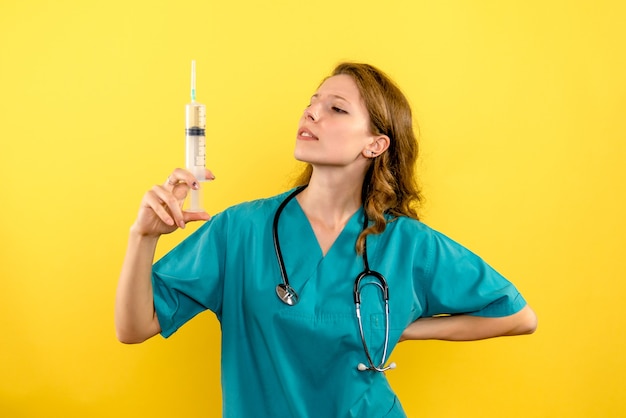 Free photo front view female doctor holding big injection on yellow space