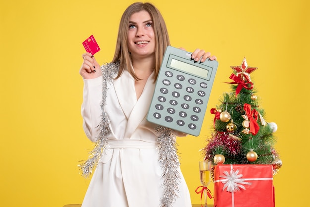 Front view female doctor holding calculator and bank card