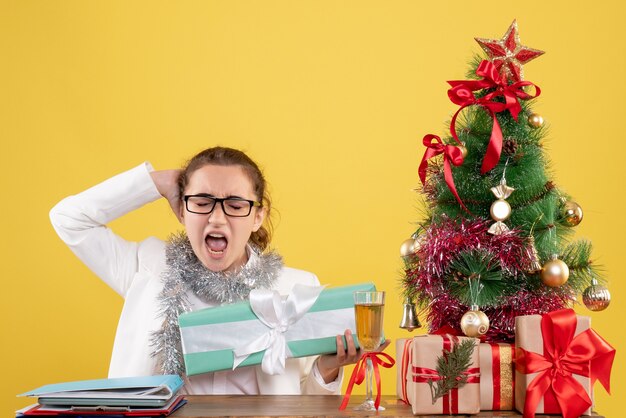 Front view female doctor holding christmas present in blue package