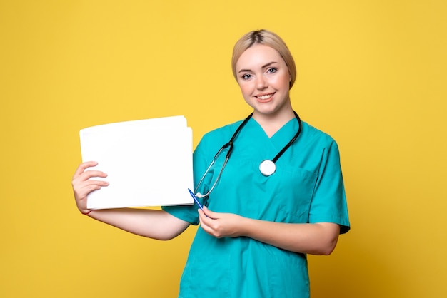 Front view female doctor holding different papers, virus pandemic health medic covid-19 nurse